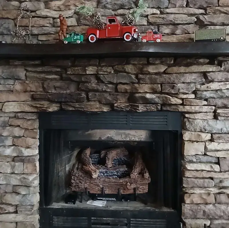 Warm stone fireplace with glowing gas logs inside our secluded Blue Ridge cabin rental